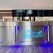 Modern stainless steel café counter with blue LED lighting at Cafe 472, featuring digital menu boards and a contemporary interior design for a trendy dining experience.